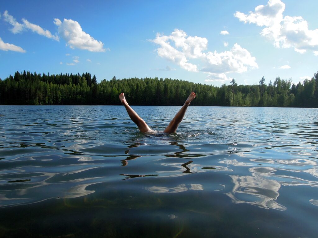 Uimassa, sukeltaa, jalat näkyy pinnalla.